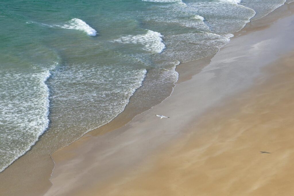 Aerial view of a tranquil beach with gentle waves along the coast of Brittany, France.