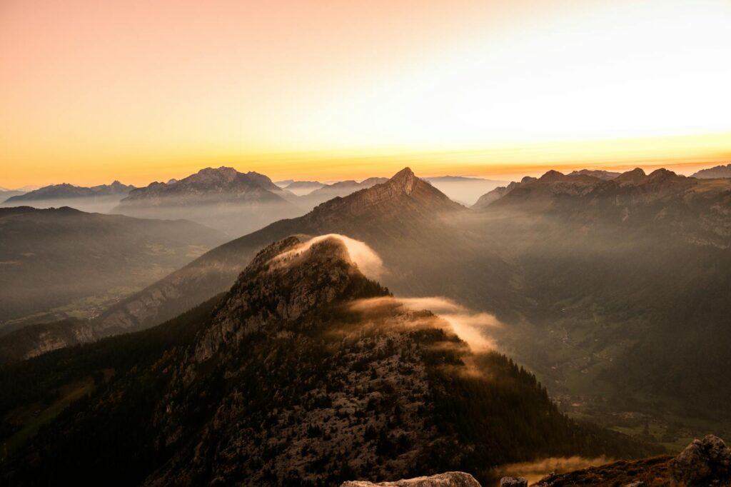 Stunning sunset view of majestic mountains with mist and golden light. Ideal for travel and adventure themes.